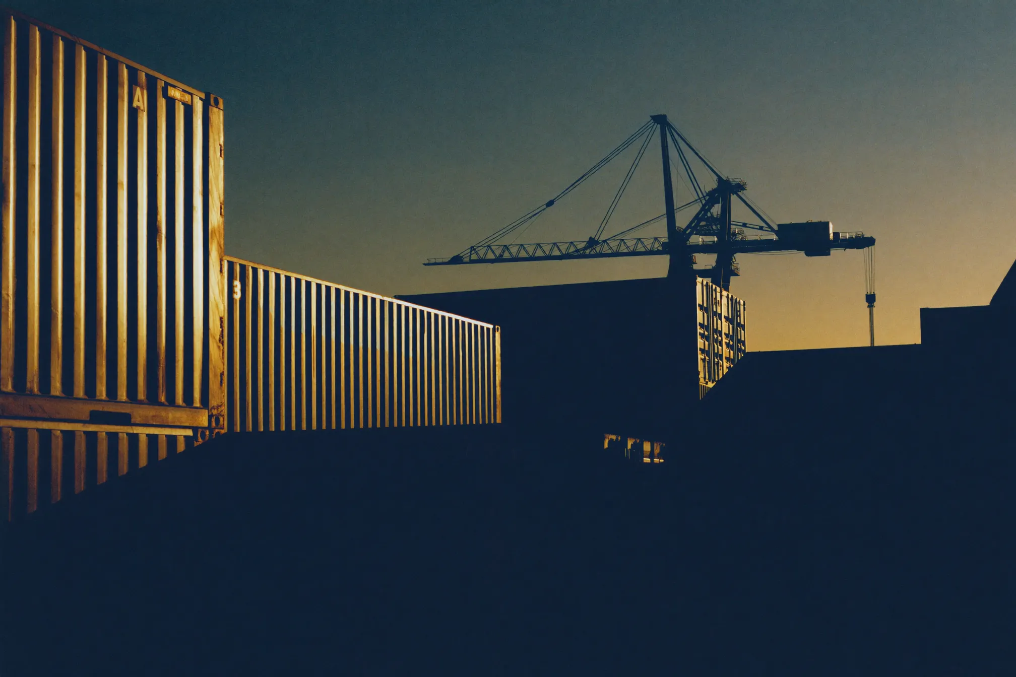 Shipping containers and a gantry crane at dusk